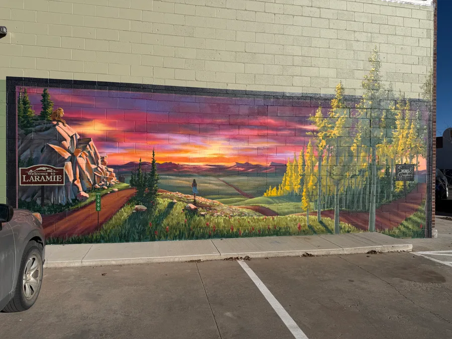 Hand-painted 'Welcome to Laramie' exterior wall mural with sunset landscape